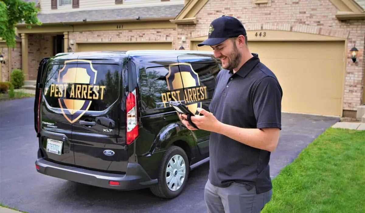 a pest control professional with the Pest Arrest company truck behind